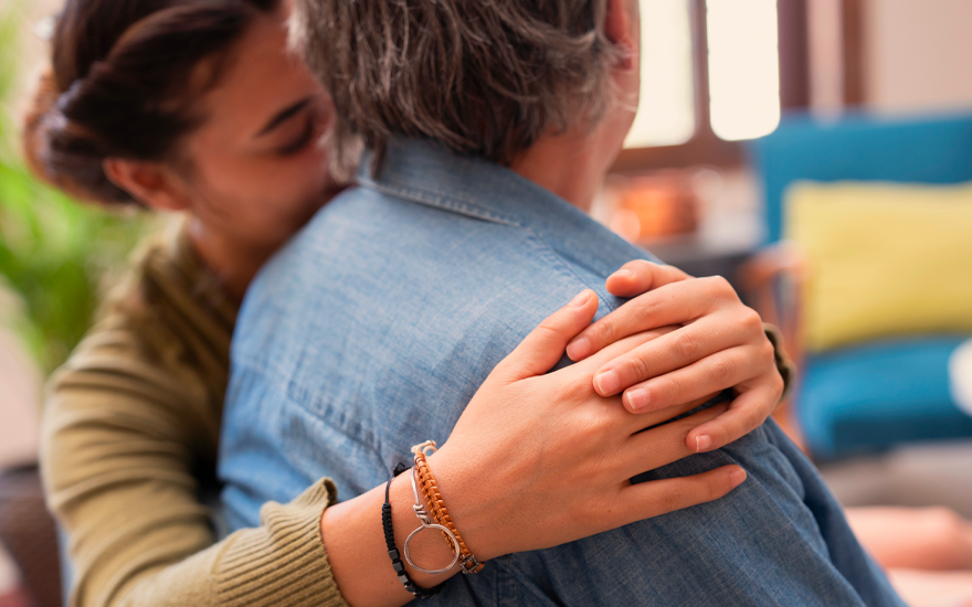 A woman holding another person closely, leaning into their shoulder.