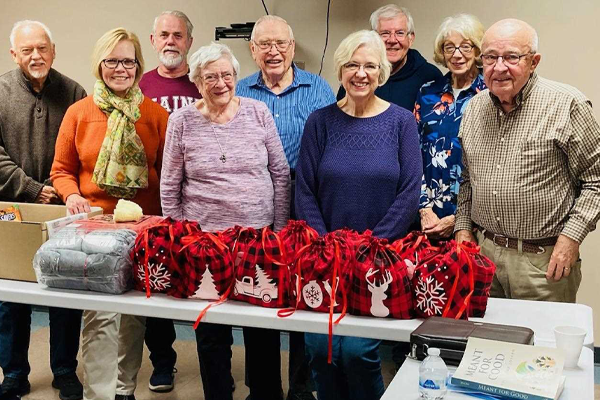 photo of Group of happy people with festive bags and items on a table in front of them.